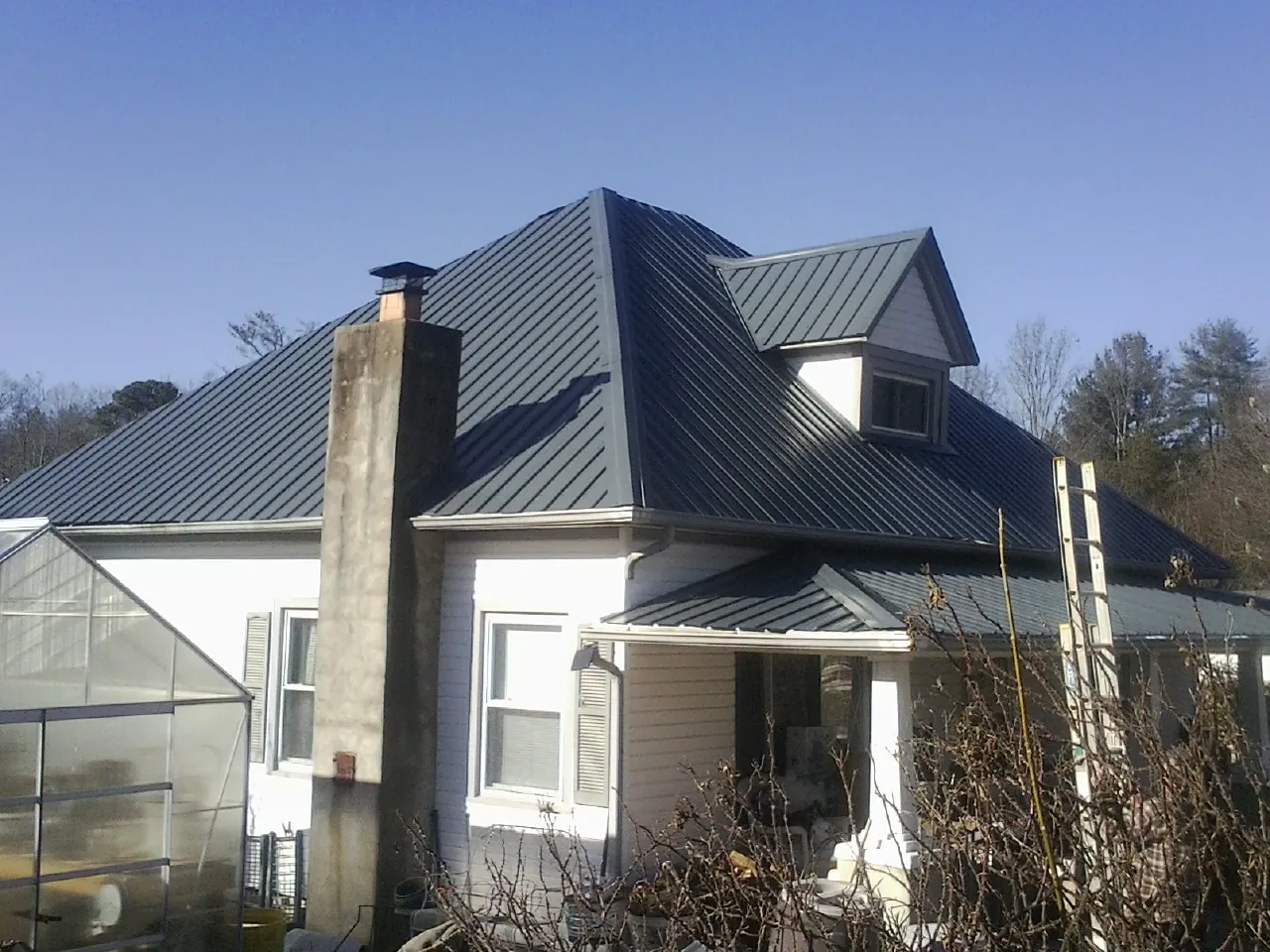 Dark blue standing seam metal roof on a white farmhouse with dormer — Slate & Tile Roof Repair by Roofing Brothers in Green Mountain Falls