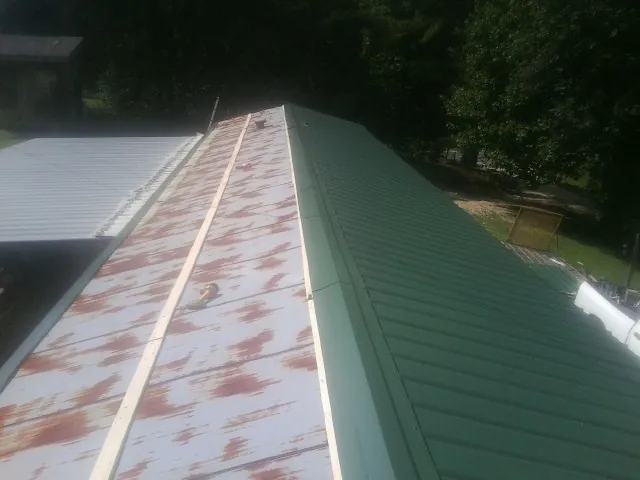 Old rusted panels beside newly installed green metal roofing — Wind Damage Roof Repair by Roofing Brothers in Green Mountain Falls