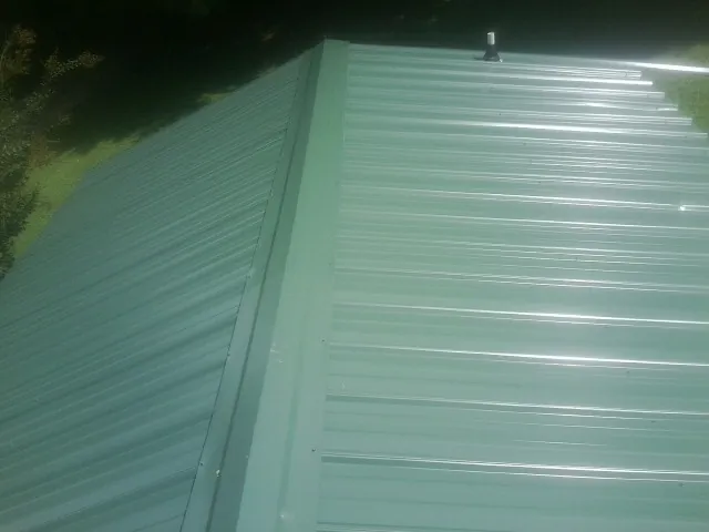 New green metal panels meeting at the ridge of a roof — Flat Roof Repair work by our crew in Green Mountain Falls