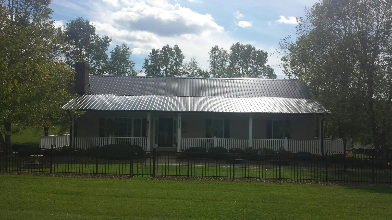 Gray metal roof on a brick ranch with a full width front porch — Gutter Guard Installation work by our crew in Green Mountain Falls