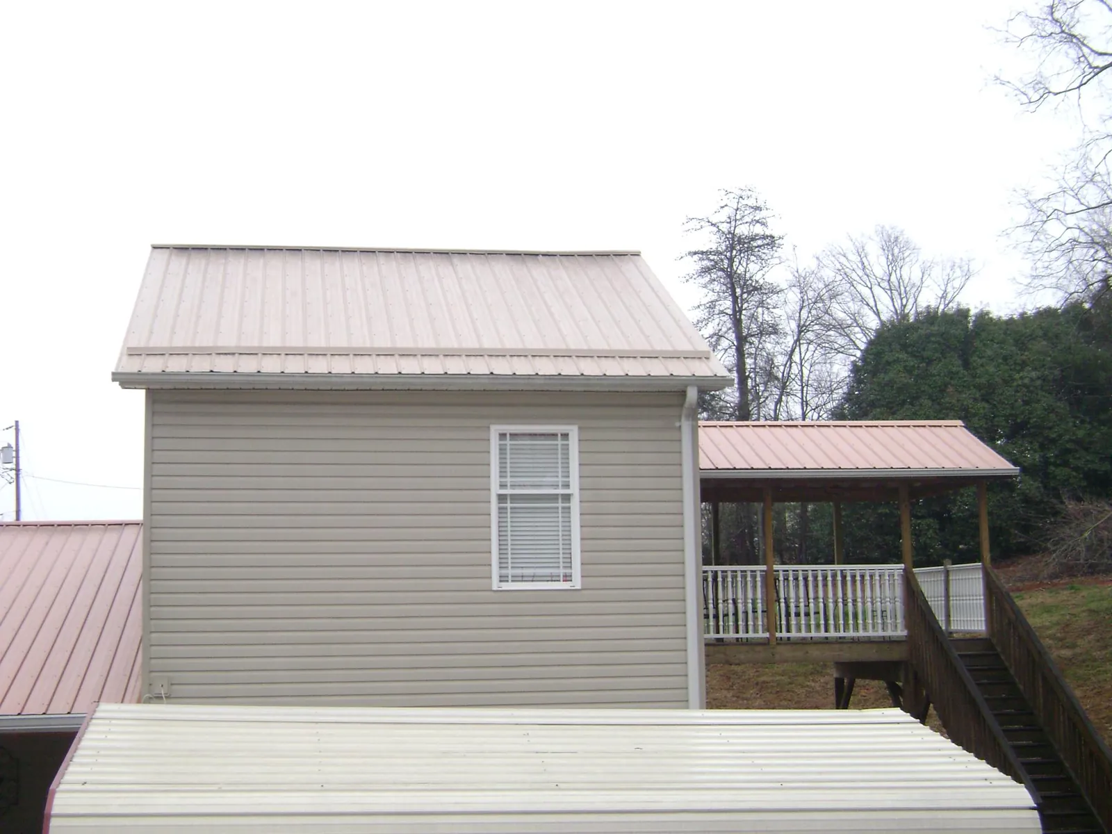 Tan metal roofs on a two story addition and attached porch, from a Roof Replacement job in Green Mountain Falls
