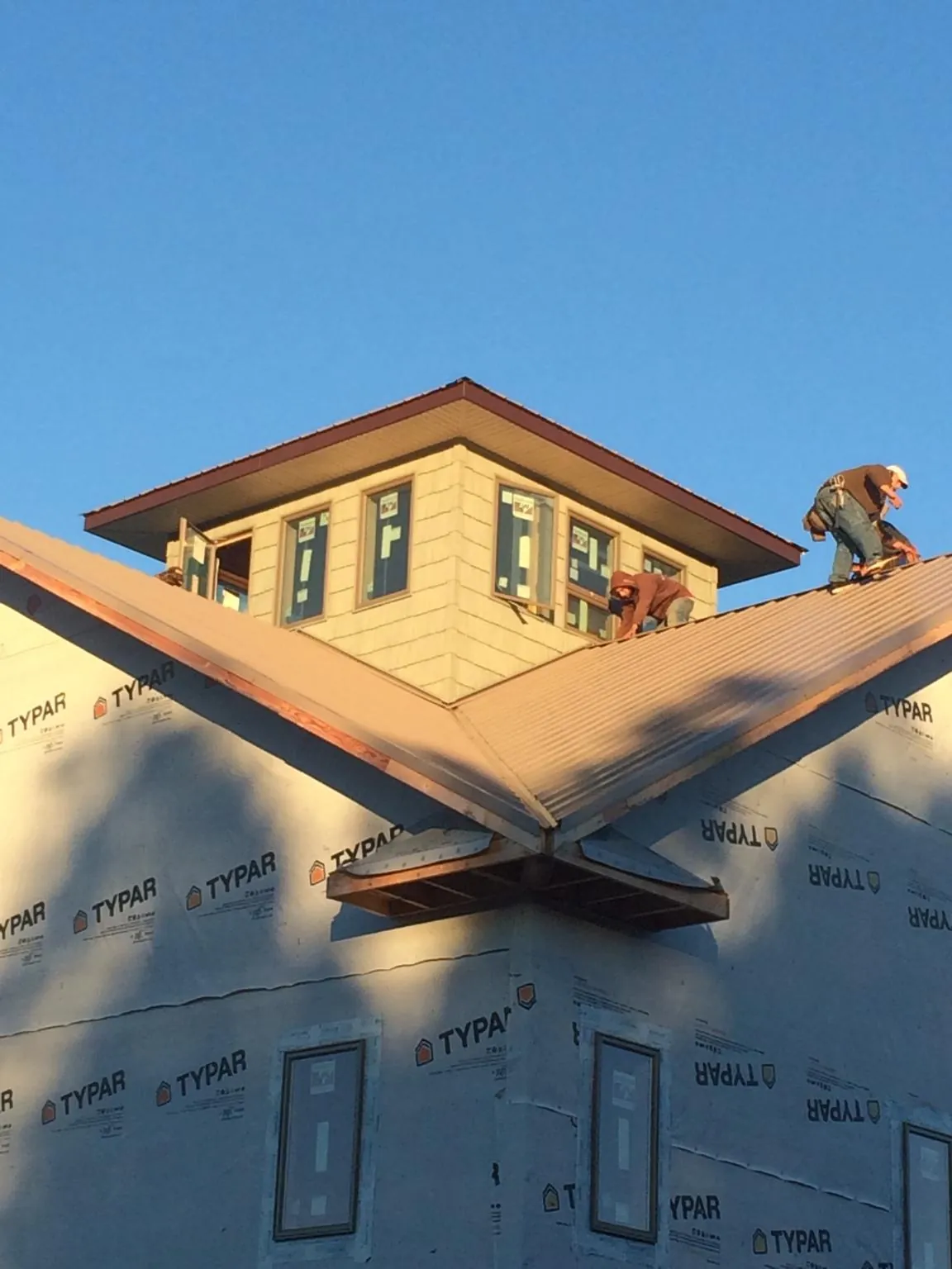 Roofers working around a rooftop cupola on a new metal roof at sunset — Roof Waterproofing in Green Mountain Falls by Roofing Brothers